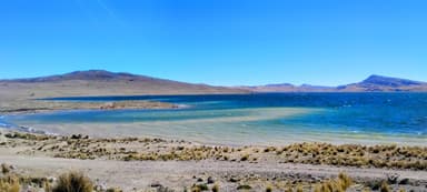 Un paysage naturel avec un lac et des montagnes sous un ciel bleu.