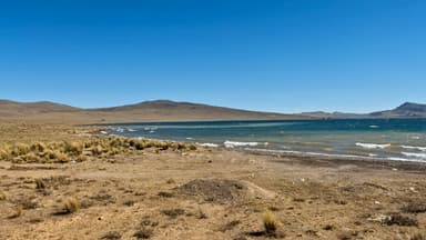 Un paysage de lac et de collines sous un ciel bleu.