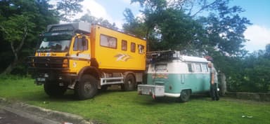 Deux véhicules de voyage stationnés sur l'herbe sous un ciel nuageux.