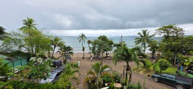 Une vue de la plage avec des palmiers et des nuages gris.