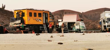Des véhicules de camping sur une plage au coucher du soleil.