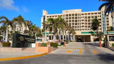 Un hôtel moderne avec des palmiers et un ciel bleu à Quintana Roo.