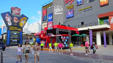 Un bâtiment coloré avec des affiches et des gens marchant devant.