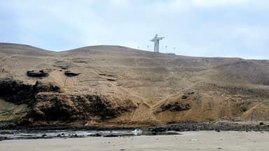 Une vue de la plage avec une colline et une statue au sommet.