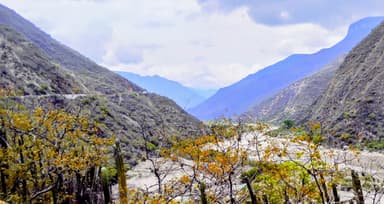 Une vue des montagnes et d'une vallée à Santander, Colombie, avec des arbres et des nuages.