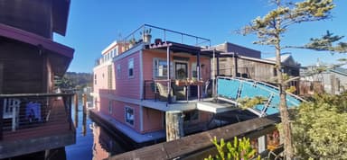 Une maison flottante colorée au bord de l'eau sous un ciel bleu.