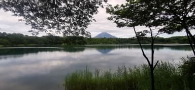 Un lac calme avec des montagnes en arrière-plan sous un ciel nuageux.