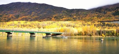 Un paysage d'automne avec un pont et des montagnes en arrière-plan.