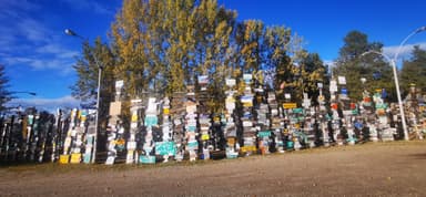 Un mur de panneaux de signalisation colorés sous un ciel bleu.