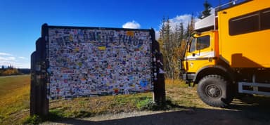Un panneau couvert de stickers sous un ciel bleu à Watson Lake.