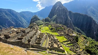 Une vue panoramique des ruines anciennes entourées de montagnes verdoyantes.