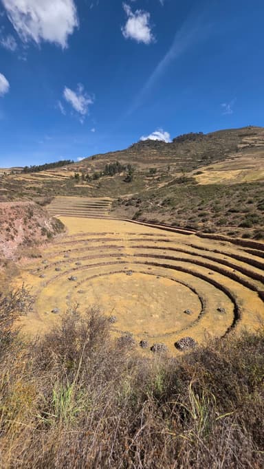 Des terrasses agricoles circulaires sous un ciel bleu à Huarocondo.