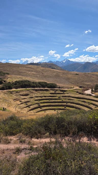 Un paysage de terrasses agricoles à Huarocondo, sous un ciel bleu.