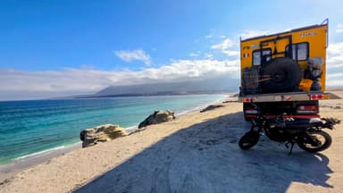 Un paysage côtier avec un véhicule et une moto au bord de la mer.