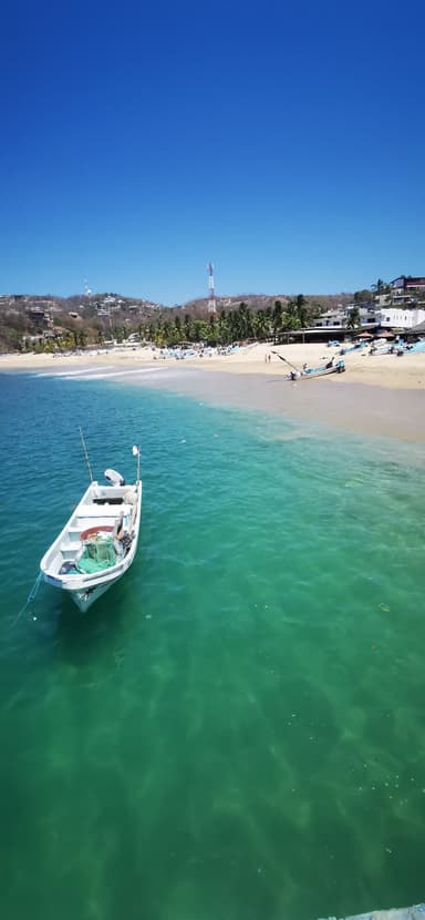 Un bateau sur une mer turquoise avec une plage en arrière-plan.