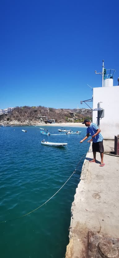 Un homme pêche au bord de l'eau sous un ciel bleu.