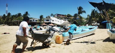 Des pêcheurs tirent des bateaux sur une plage ensoleillée.
