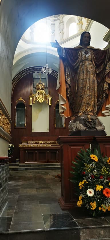 Une statue religieuse dans une église avec des fleurs colorées.