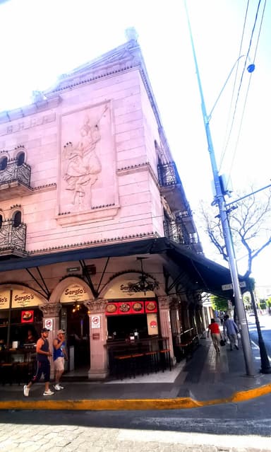Un bâtiment avec une façade ornée et des personnes marchant devant.