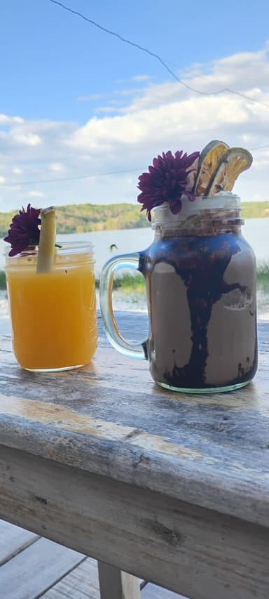 Deux boissons sur une table en bois avec un paysage en arrière-plan.