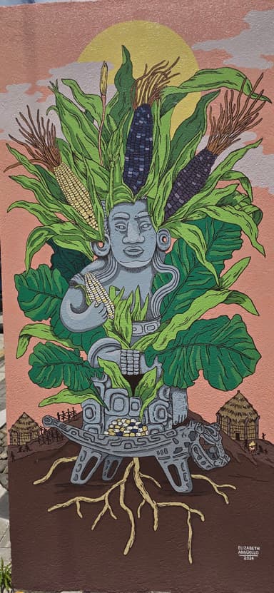 Une fresque murale colorée représentant une statue avec des plantes et du maïs.
