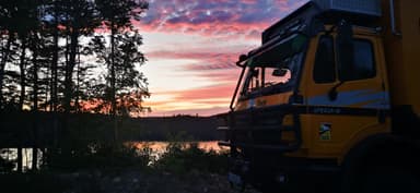 Un camion jaune au coucher du soleil près d'un lac.