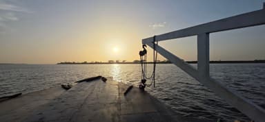 Un coucher de soleil sur un fleuve avec un bateau en bois.