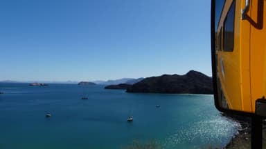 Une vue de la mer turquoise avec des bateaux et des montagnes au loin.