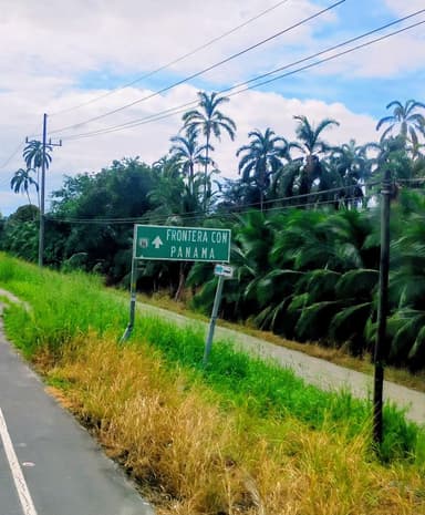 Un panneau indiquant la frontière avec le Panama, entouré de verdure.