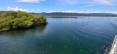 Une vue paisible d'une rivière entourée de végétation sous un ciel bleu.