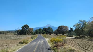 A scenic road leading towards a mountain under a clear blue sky.