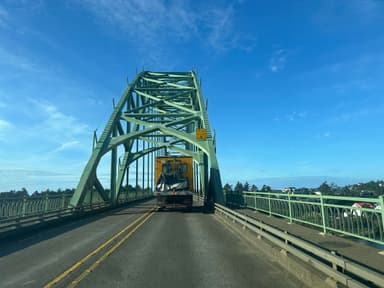 Un pont vert avec un camion sur la route sous un ciel bleu.