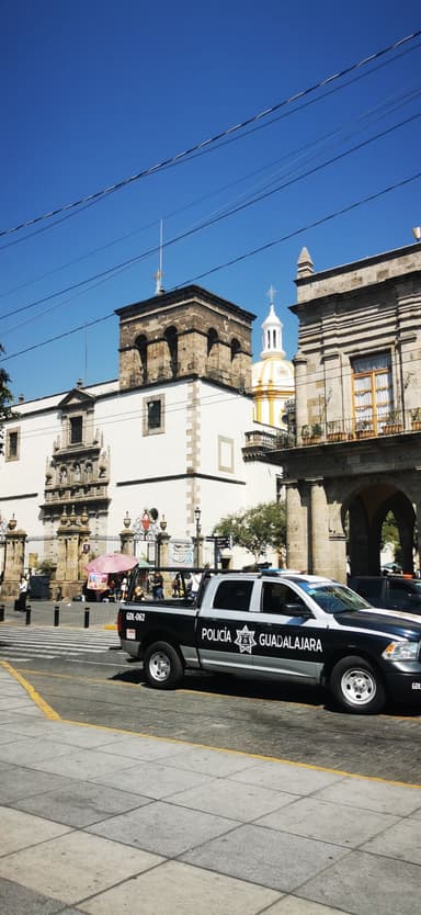 Un bâtiment historique avec un véhicule de police à Guadalajara sous un ciel bleu.