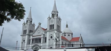 Une église blanche avec des tours sous un ciel nuageux.