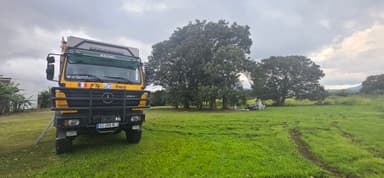 Un camion garé sur une pelouse verte sous un ciel nuageux.