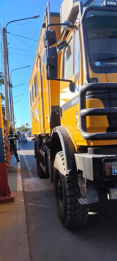 Un camion jaune garé sur une rue ensoleillée.