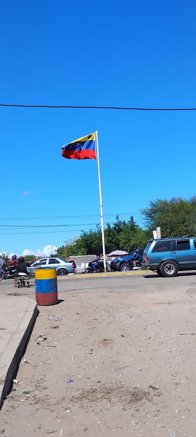 Un drapeau vénézuélien flotte sous un ciel bleu.
