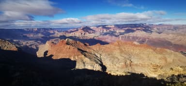Une vue panoramique des formations rocheuses et des montagnes sous un ciel bleu.