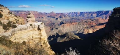 Un paysage du Grand Canyon avec des formations rocheuses et des montagnes au loin.