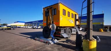 Un camion jaune avec une remorque dans un stationnement ensoleillé.