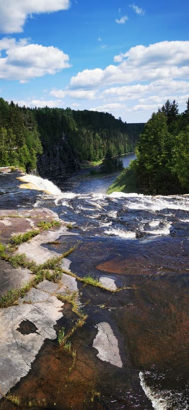 Une vue d'une rivière et des chutes d'eau sous un ciel bleu avec des nuages.