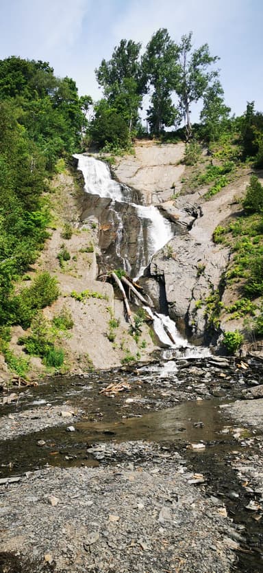 Une cascade entourée de verdure et de rochers.