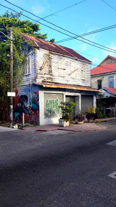 Une maison avec une fresque murale à Belize City sous un ciel bleu.