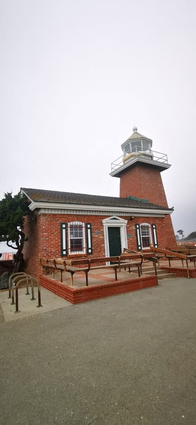 Un phare en briques sous un ciel nuageux.