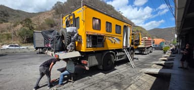 Un camion jaune stationné avec des réparations en cours sous un ciel bleu.