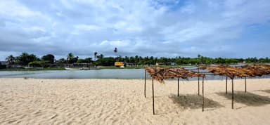 Une plage avec des abris en bois et un bateau sur l'eau.