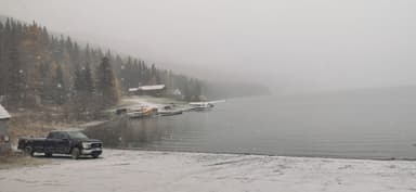 A snowy lakeside scene with seaplanes and a truck parked nearby.
