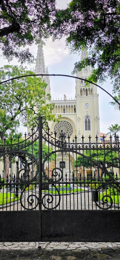 Une église avec des tours et un jardin verdoyant devant elle.