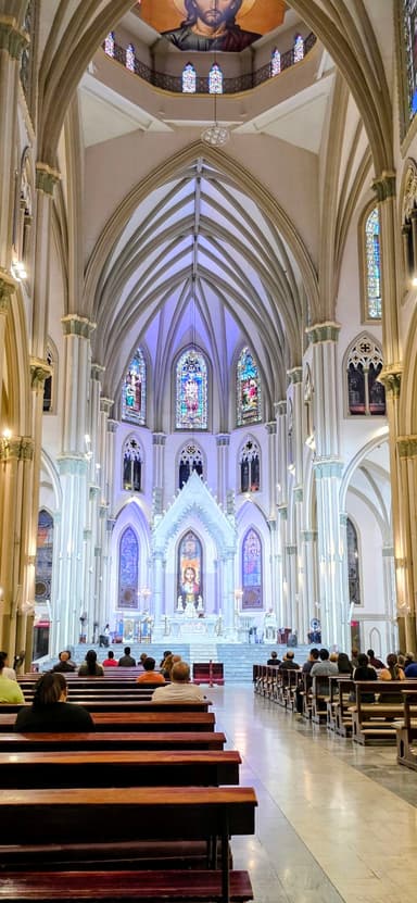 Une église avec des vitraux et des bancs remplis de personnes.