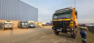 A parking area with various vehicles, including a large truck, under a clear sky.
